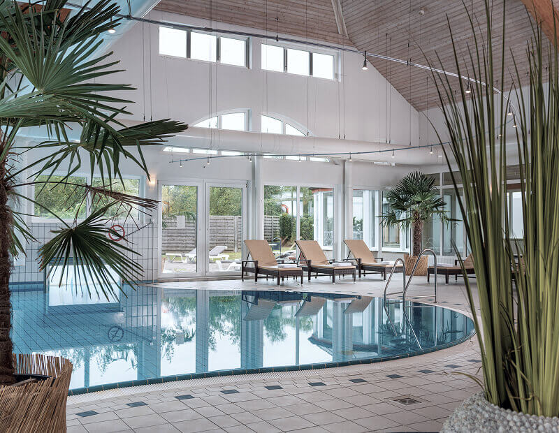 strandhotel-sylt-fruehstueck Innenpool mit Palmen und Liegen