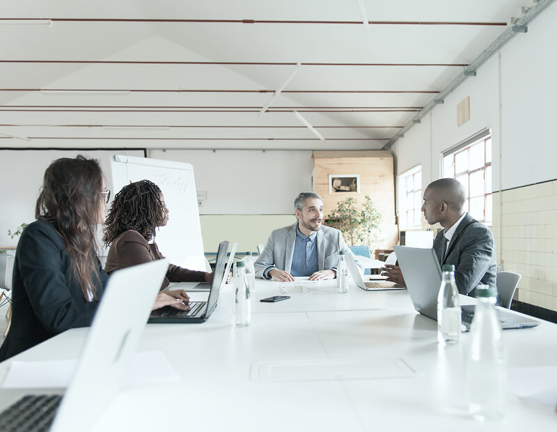 Mehrere Menschen sitzen an einm großen Tisch und halten ein Meeting
